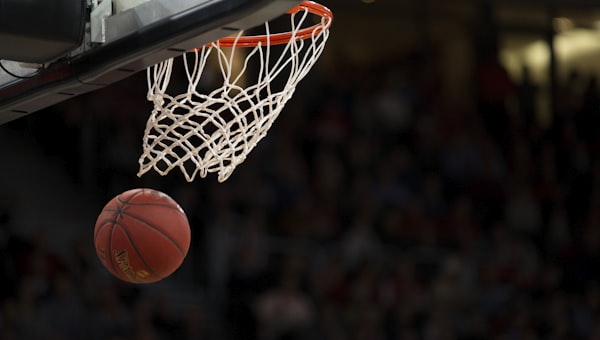 NBA篮球赛场上球员高高跃起完成精彩扣篮的瞬间特写，气氛热烈