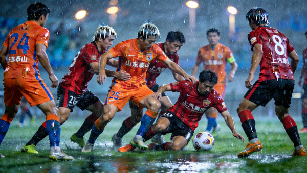 中超联赛山东泰山队与上海海港队球员在雨中激烈拼抢的比赛画面
